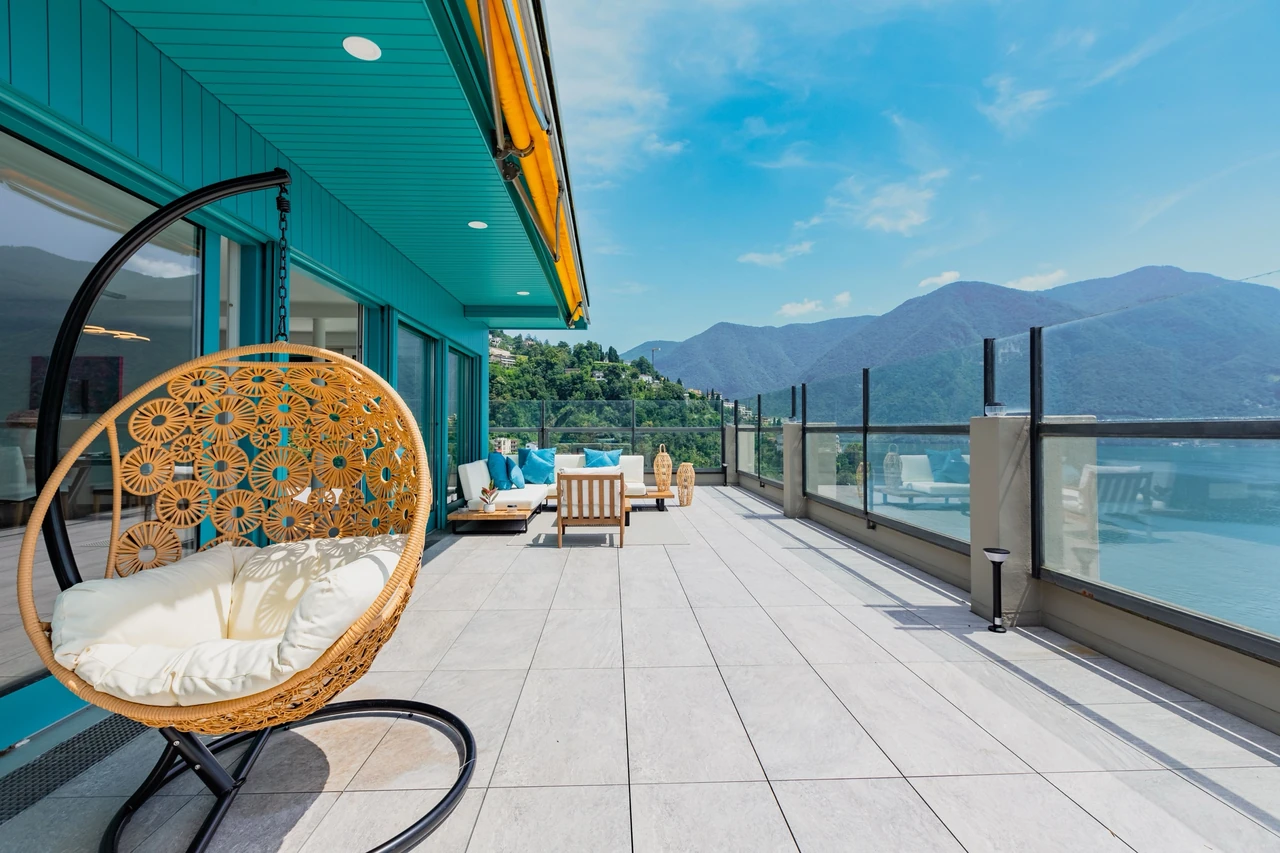 Grande terrasse avec fauteuil suspendu, vue sur un lac et des montagnes