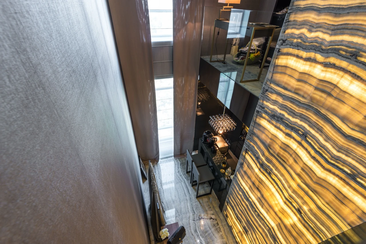 Atrium sur double hauteur avec mur en onyx rétroéclairé et sol en marbre